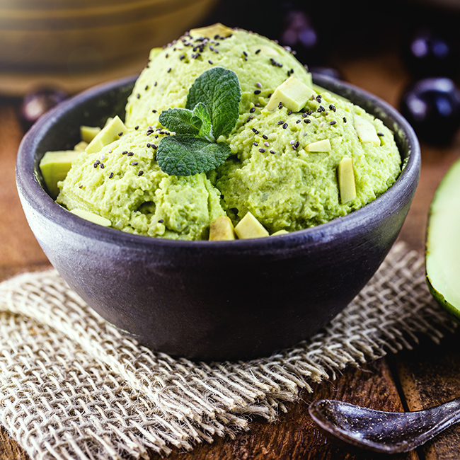 organic and natural avocado ice cream, without preservatives, with tropical fruits from brazil in the background, served in handmade clay bowl, gourmet ice cream